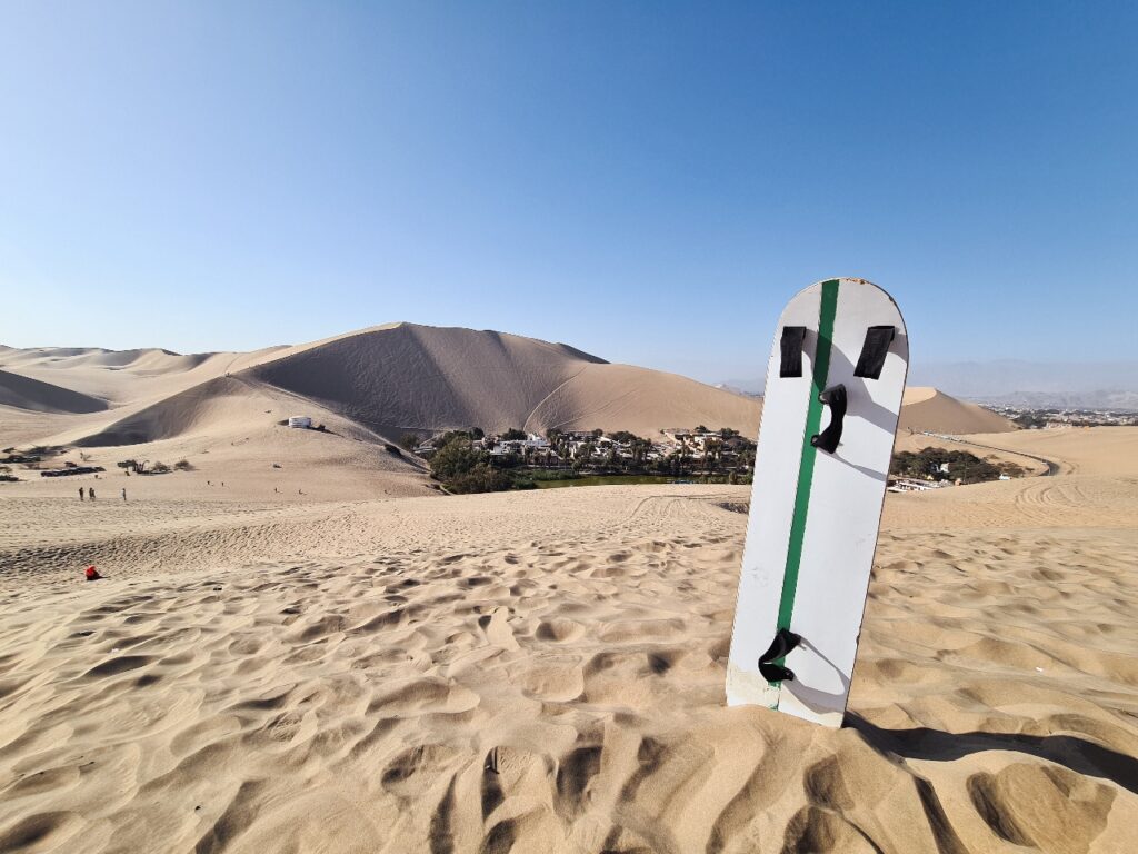 Deska do sandboardingu wbita w piasek na pustyni Huacachina