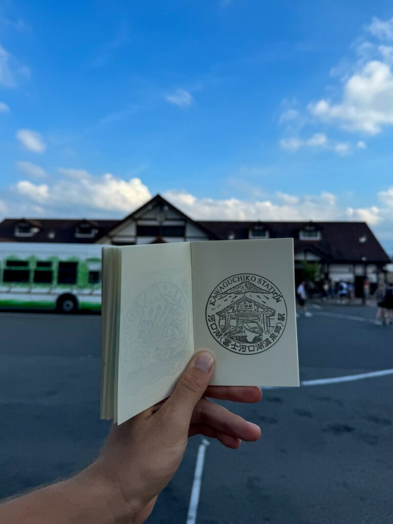 Notes na japońskie Eki Stamps. Pieczątka z Kawaguchiko Station na tle tej stacji