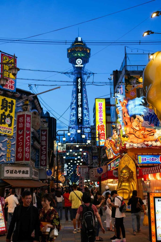 Wieża obserwacyjna Tsūtenkaku widziana z ulicy tętniącej życiem.