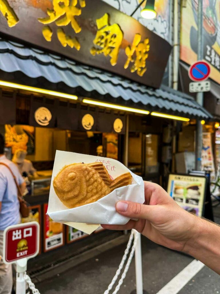 Taiyaki w ręku na tle restauracji, w której są serwowane.