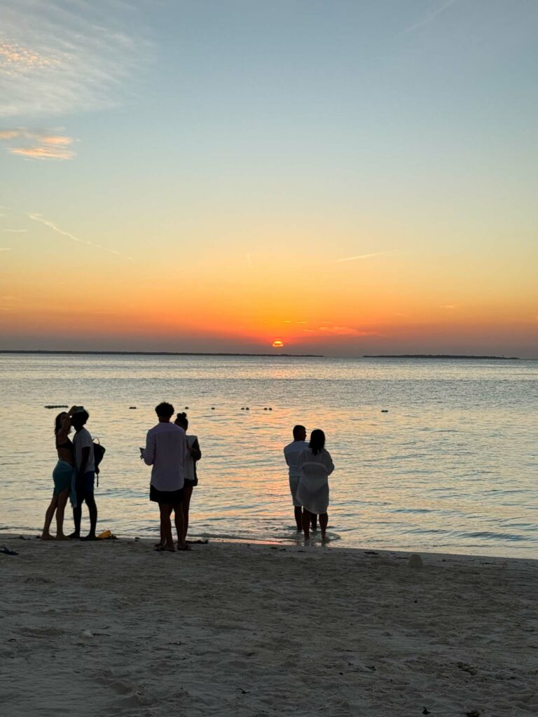 Trzy pary na brzegu podczas zachodu słońca na Kendwa Beach na Zanzibarze.