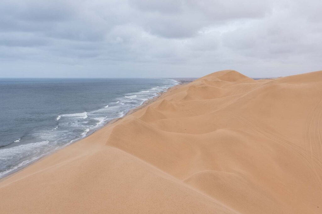 Fale oceanu oraz pustynia. Sandwich Harbour, Namibia.